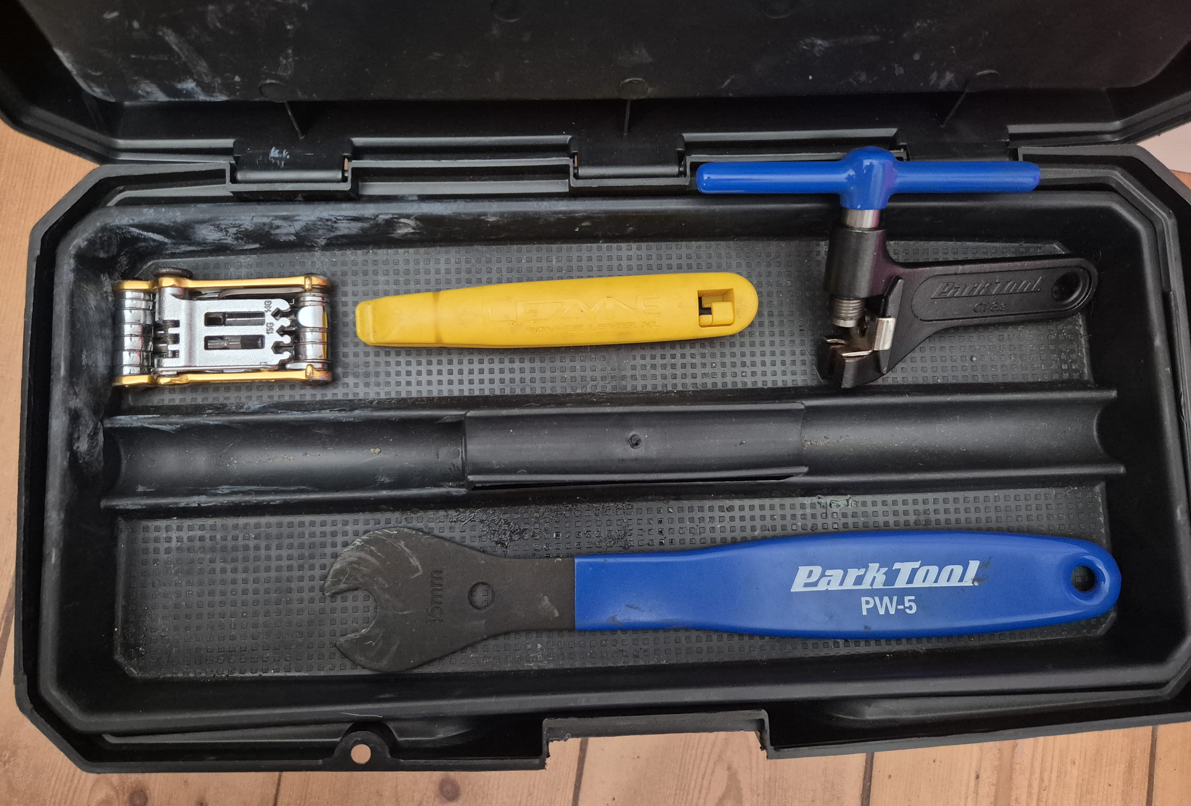 The toolbox with the lid open to reveal a collection of 4 different bicycle maintenance tools sitting on a tray.